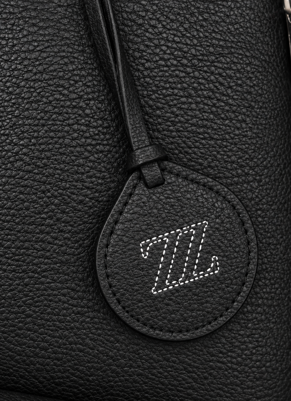 Detalle de piel flotter y logo AMZZUL en bolsa tote negra