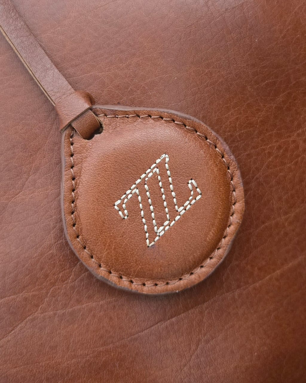Detalle de piel y logo AMZZUL en bolsa tote miel